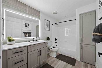 an all white bathroom with gray cabinets and a black shower curtain